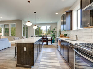Custom kitchen with dark cabinetry, patterned wood flooring, and brick backsplash