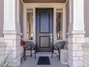 Dark wooden front entry door with sidelights and patio furniture