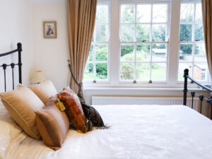 Bedroom with pretty white window that has sunlight shining through