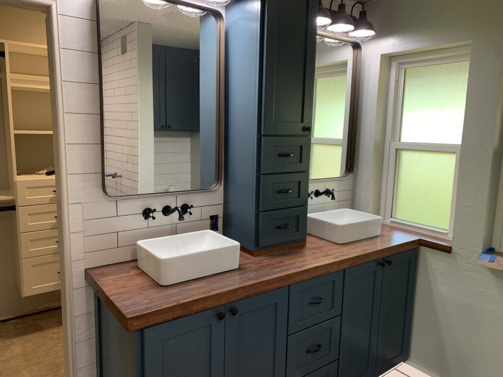 Bathroom remodel with blue vanity, wood countertop, updated sink, and simple finish selections.