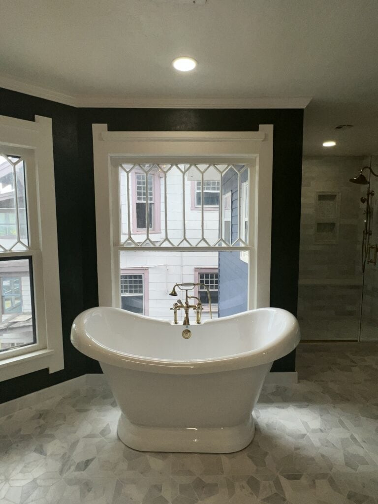 Luxury bathroom remodel with freestanding tub, tile shower, large window, and upgraded finishes.