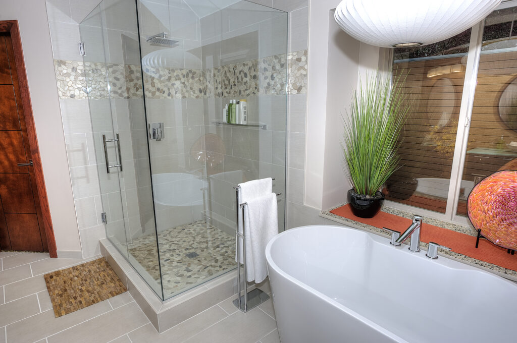 Custom tile shower remodel with walk-in layout, niche, bench, and dark tile.